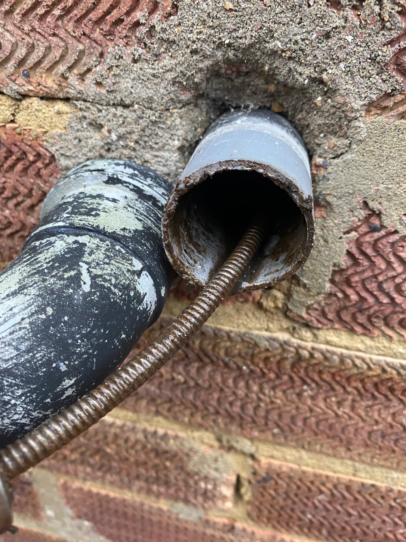 Drain cable being fed into an external waste pipe to unblock a kitchen sink waste in Folkestone, Kent, by First Response Drains